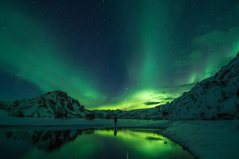 Aurora boreal sobre montañas nevadas en Islandia