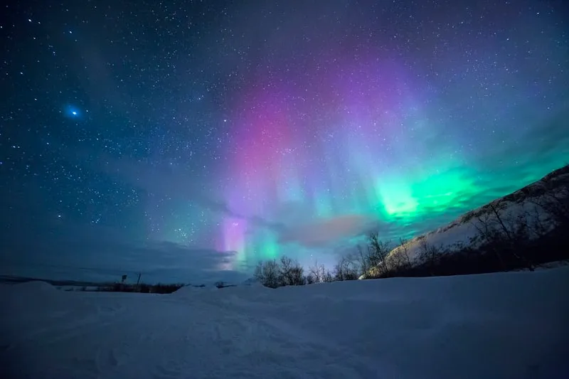 Aurora boreal sobre montañas nevadas en Noruega